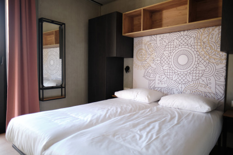 Modern slaapvertrek in Resort Gulpen 5 in Nederland met dubbel bed en artistiek muurontwerp.