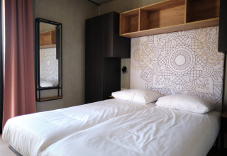 Modern slaapvertrek in Resort Gulpen 5 in Nederland met dubbel bed en artistiek muurontwerp.