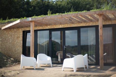 Buitenruimte met vier witte stoelen voor een stenen lodge bij Resort Gulpen 5, Nederland.