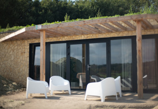 Buitenruimte met vier witte stoelen voor een stenen lodge bij Resort Gulpen 5, Nederland.
