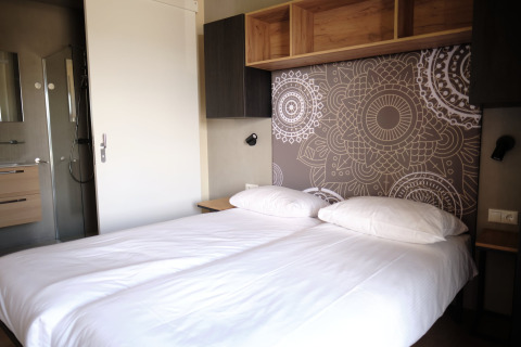 Moderne tweepersoonskamer met mandala hoofdboard en privébadkamer in Resort Gulpen 5, Nederland.