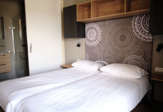 Moderne tweepersoonskamer met mandala hoofdboard en privébadkamer in Resort Gulpen 5, Nederland.