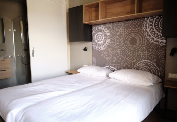 Moderne dobbeltværelse med geometrisk mønstret hovedgærde og privat badeværelse på Resort Gulpen 5.