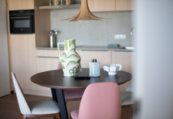 Moderne køkken og spisebord med keramisk vase, pastelfarvede stole og indretning på Resort Gulpen 5 i Holland.