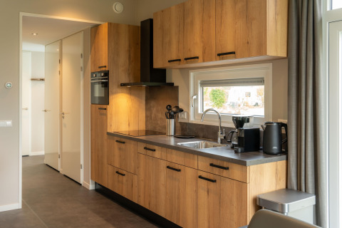 Cucina moderna da lodge con armadietti in legno, forno, finestra, bollitore elettrico e macchina da caffè.