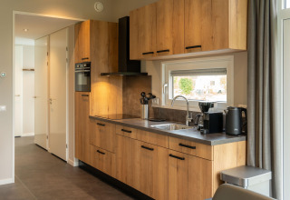 Cucina moderna da lodge con armadietti in legno, forno, finestra, bollitore elettrico e macchina da caffè.