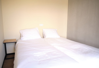 Tweepersoonsbed met witte lakens en twee kussens in een slaapkamer van Resort Gulpen 4 in Nederland.