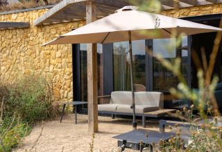 Coin salon extérieur avec parasol et mur en pierre au Resort Gulpen 4, Pays-Bas, vu de jour.
