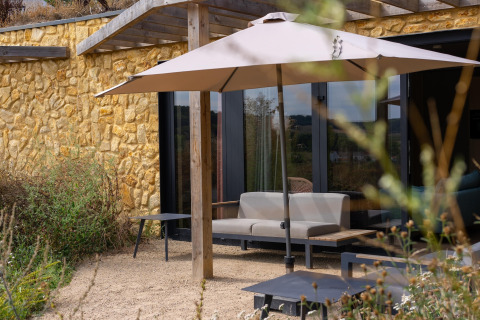 Udendørs loungeområde med parasol, bænk og stenmur på Resort Gulpen 4, Holland, set i dagslys.