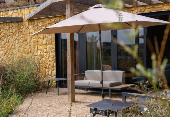 Buitenzithoek met parasol en natuurstenen muur aan Resort Gulpen 4, Nederland, op klaarlichte dag.