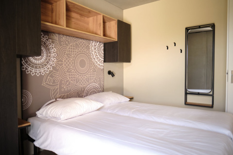 Moderne lodgeværelse på Resort Gulpen 4 i Holland med to senge, åbne hylder og vægdekoration.