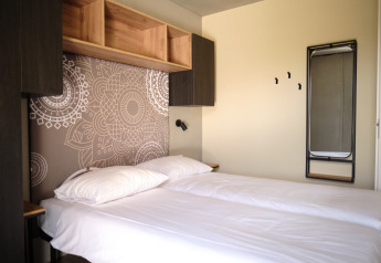 Moderne lodgekamer bij Resort Gulpen 4 in Nederland met twee bedden, opbergrekken en wandkunst.