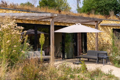 Udendørsbillede af Resort Gulpen 4-lodge i Holland med have, terrasse og siddeområde under parasol.