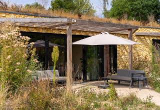 Udendørsbillede af Resort Gulpen 4-lodge i Holland med have, terrasse og siddeområde under parasol.