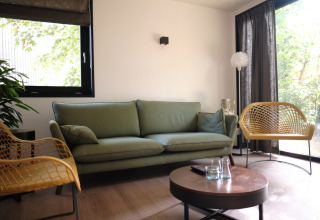 Salon moderne au Resort Gulpen 8 aux Pays-Bas avec canapé vert, fauteuils jaunes et grandes fenêtres lumineuses.