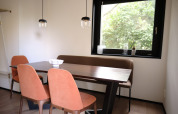 Comedor en Resort Gulpen 8 en los Países Bajos con mesa moderna, sillas y una gran ventana con vista verde.