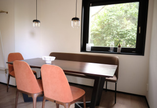 Coin repas au Resort Gulpen 8 aux Pays-Bas avec table moderne, chaises et grande fenêtre sur la verdure.
