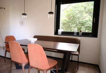 Comedor en Resort Gulpen 8 en los Países Bajos con mesa moderna, sillas y una gran ventana con vista verde.