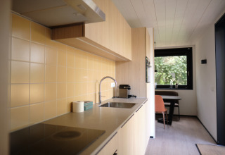 Cuisine moderne du Resort Gulpen 8, Pays-Bas, avec carrelage jaune, plaque de cuisson et coin repas près de la fenêtre.