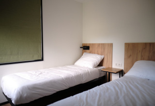 Chambre moderne avec deux lits simples et têtes de lit en bois au Resort Gulpen 8 aux Pays-Bas.