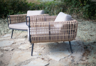 Fauteuils d’extérieur en rotin avec coussins au Resort Gulpen 8, Pays-Bas, sur terrasse en pierre.