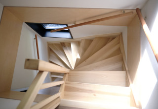 Escalier en colimaçon en bois clair avec puits de lumière vu d’en haut au Resort Gulpen 8, Pays-Bas.
