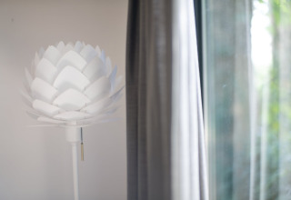 Lampe moderne blanche en forme de fleur près d’un rideau au Resort «Gulpen 8» aux Pays-Bas, intérieur.