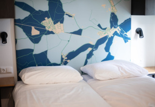 Chambre moderne avec deux lits simples, linge blanc et tête de lit décorée d'une carte au Resort Gulpen 7.