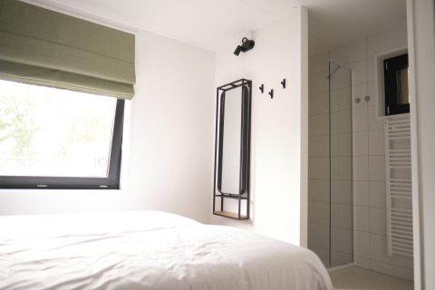 Lichte slaapkamer met groot raam, bed en moderne ensuite badkamer in Resort Gulpen 7, Nederland.