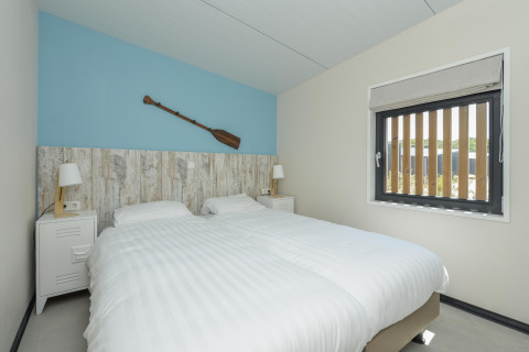 Moderne slaapkamer in Sea Lodges Bloemendaal 5 in Nederland met twee aparte bedden en een roeispaan als decoratie.