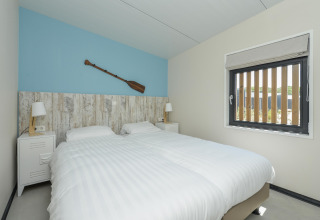 Moderne slaapkamer in Sea Lodges Bloemendaal 5 in Nederland met twee aparte bedden en een roeispaan als decoratie.