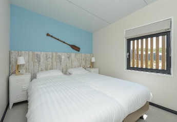 Chambre moderne aux Sea Lodges Bloemendaal 5 aux Pays-Bas, avec deux lits simples et une décoration nautique.