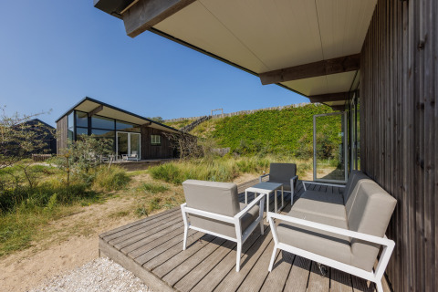 Buitenterras met comfortabele zitbanken bij Sea Lodges «Bloemendaal 5» in Nederland, tussen het groen.