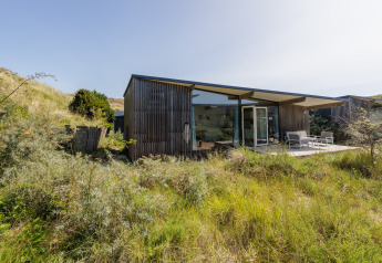 Lodge moderne aux Sea Lodges Bloemendaal 5 aux Pays-Bas, entouré de dunes herbeuses et de nature sauvage.