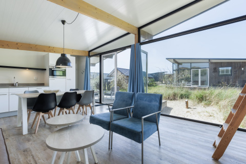 Lichte, moderne leefruimte in Sea Lodges Bloemendaal 5, Nederland, met grote ramen en uitzicht op de natuur.