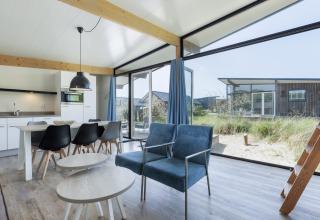 Lichte, moderne leefruimte in Sea Lodges Bloemendaal 5, Nederland, met grote ramen en uitzicht op de natuur.