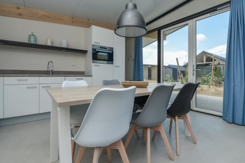 Moderne eetkamer met trendy stoelen, veel licht en zicht naar buiten in Sea Lodges Bloemendaal 5, Nederland.