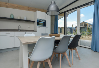 Moderne eetkamer met trendy stoelen, veel licht en zicht naar buiten in Sea Lodges Bloemendaal 5, Nederland.