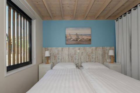 Slaapkamer in Sea Lodges Bloemendaal 5 in Nederland, twee aparte bedden en een houten plafond.
