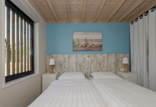 Slaapkamer in Sea Lodges Bloemendaal 5 in Nederland, twee aparte bedden en een houten plafond.