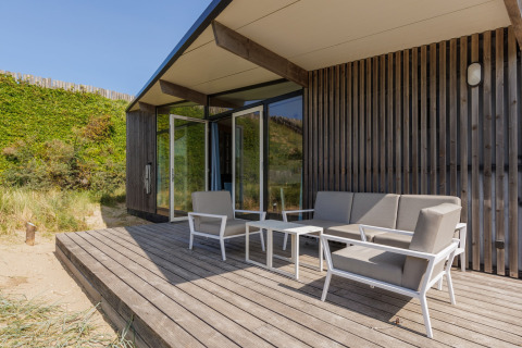 Houten terras met moderne lounge bij Sea Lodges Bloemendaal 5, omgeven door duinen in Nederland.