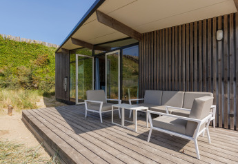 Terrasse en bois avec salon moderne aux Sea Lodges Bloemendaal 5, entourée de dunes aux Pays-Bas.
