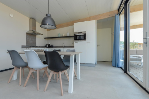 Moderne eet- en keukenruimte in Sea Lodges Bloemendaal 5 met stijlvolle stoelen en grote ramen.