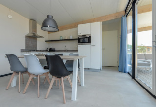 Moderne eet- en keukenruimte in Sea Lodges Bloemendaal 5 met stijlvolle stoelen en grote ramen.