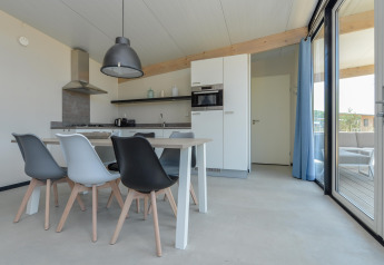 Coin repas et cuisine moderne aux Sea Lodges Bloemendaal 5 avec chaises design et grandes baies vitrées.