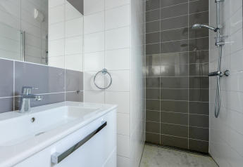 Salle de bain moderne avec lavabo, robinet chromé, et douche aux Sea Lodges «Bloemendaal 5» aux Pays-Bas.