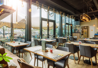 Espace restaurant lumineux et moderne dans un site de glamping, avec de grandes baies vitrées.