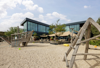 Buiten speelzone met robuuste houten structuur aan een moderne glamping met glazen voorgevel.