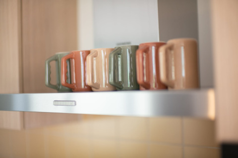 Cinq mugs colorés posés en rang sur une étagère de cuisine au Resort «Gulpen 7» aux Pays-Bas.