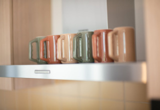 Cinq mugs colorés posés en rang sur une étagère de cuisine au Resort «Gulpen 7» aux Pays-Bas.